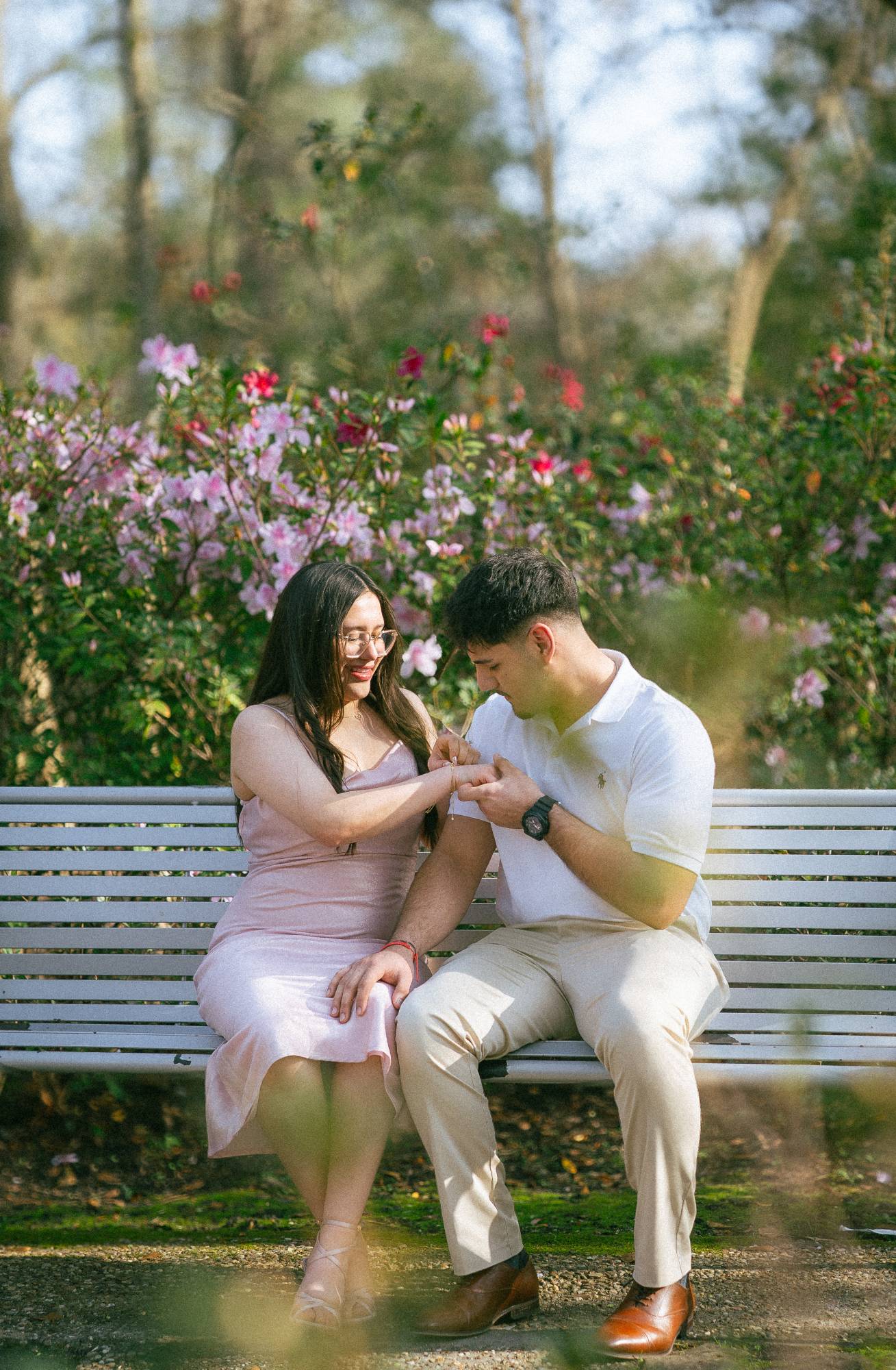 Couple sitting on a garden bench among pink azaleas before a proposal in Houston